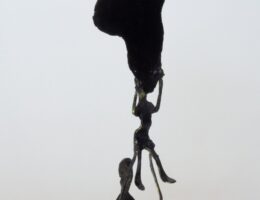 Escultura de metal pintando en negro, una figura humana sostiene a otra figura que, a su vez, sostiene el mapa del continente africano.